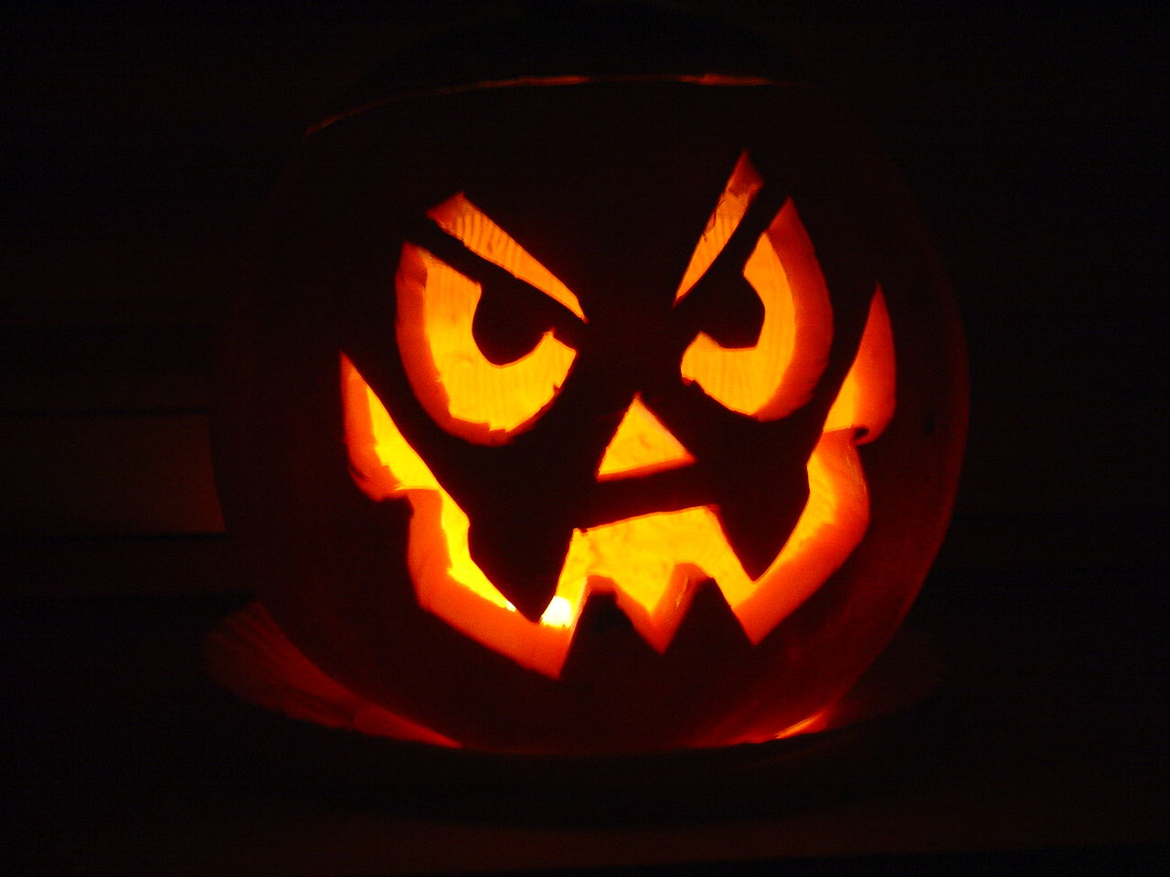 photo of a jack o lantern with a mischievious face, illuminated from within on a black background